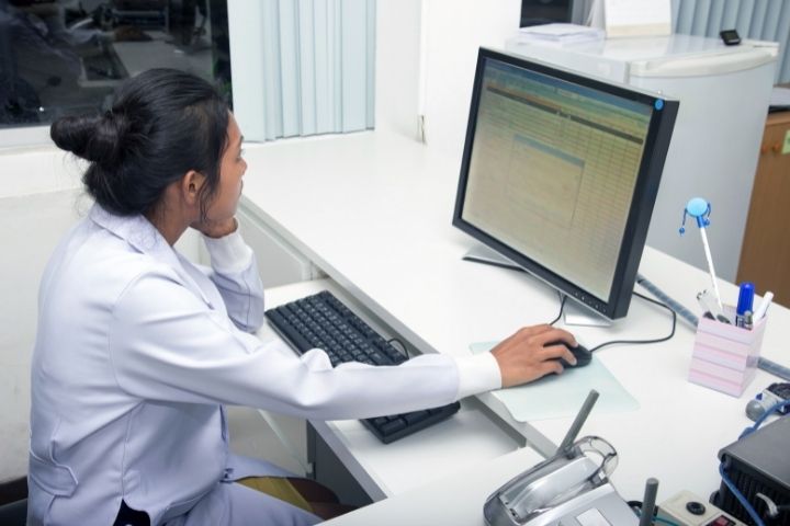 Person in medical career sits at computer in an office working on billing and coding.