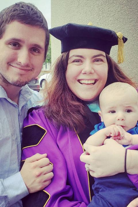 Allison Plattsmier in graduation attire beside partner with baby in hand