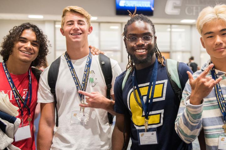 Male Freshmen Orientation participants smiling and displaying the Power C hand sign