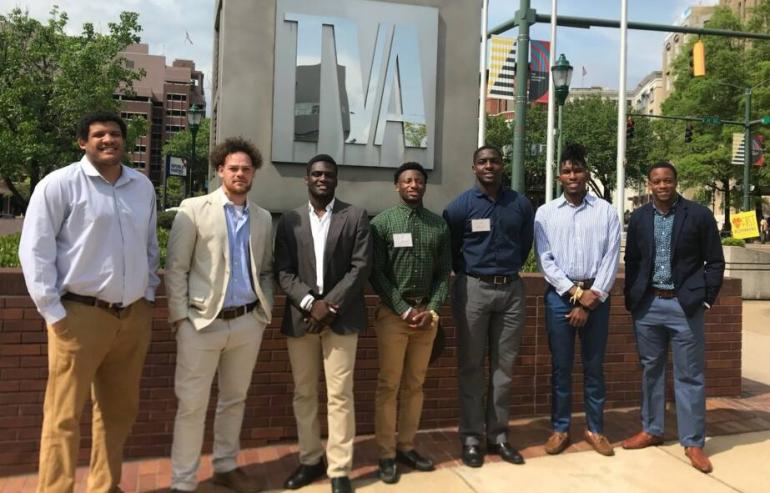 group of business students stand outside in front of TVA sign during job shadowing at the local business
