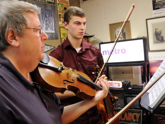 Student and teacher playing violin in classroom
