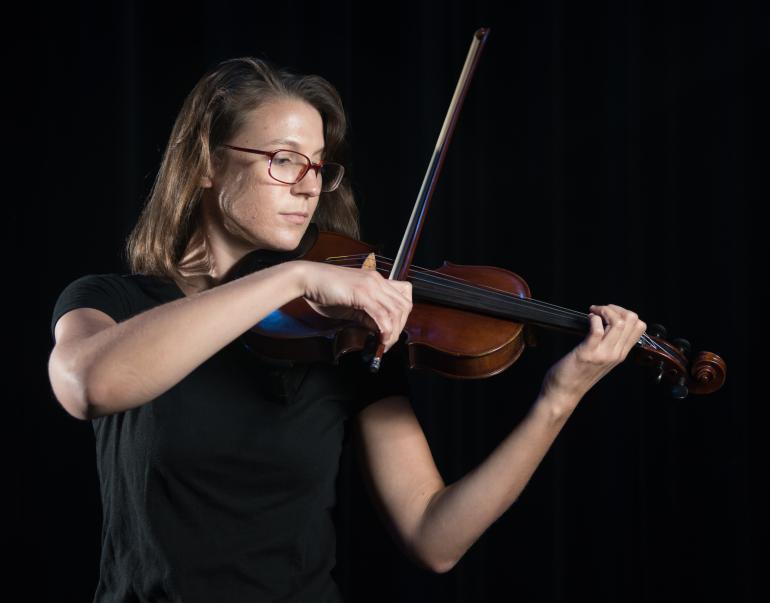 Woman playing violin with a black background